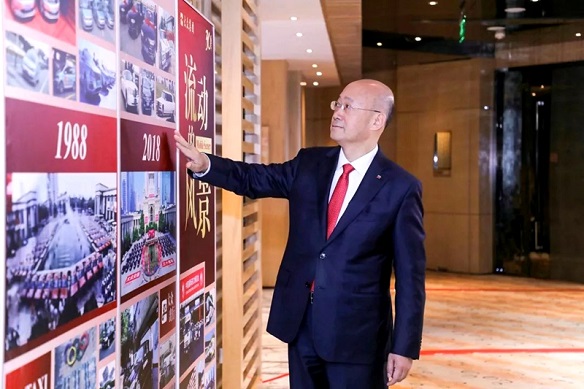 大家在大众30周年照片墙 驻足观看集团董事长杨国平在平安果上写下"祝