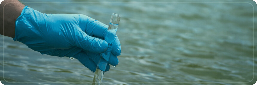 A hand with blue glove holding a tube for water quality testing