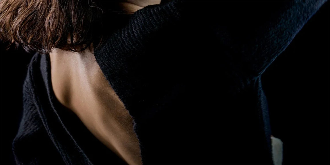 Close-up-detail-photo-of-young-woman-wearing-open-back-blouse-on-black-background.webp.jpg