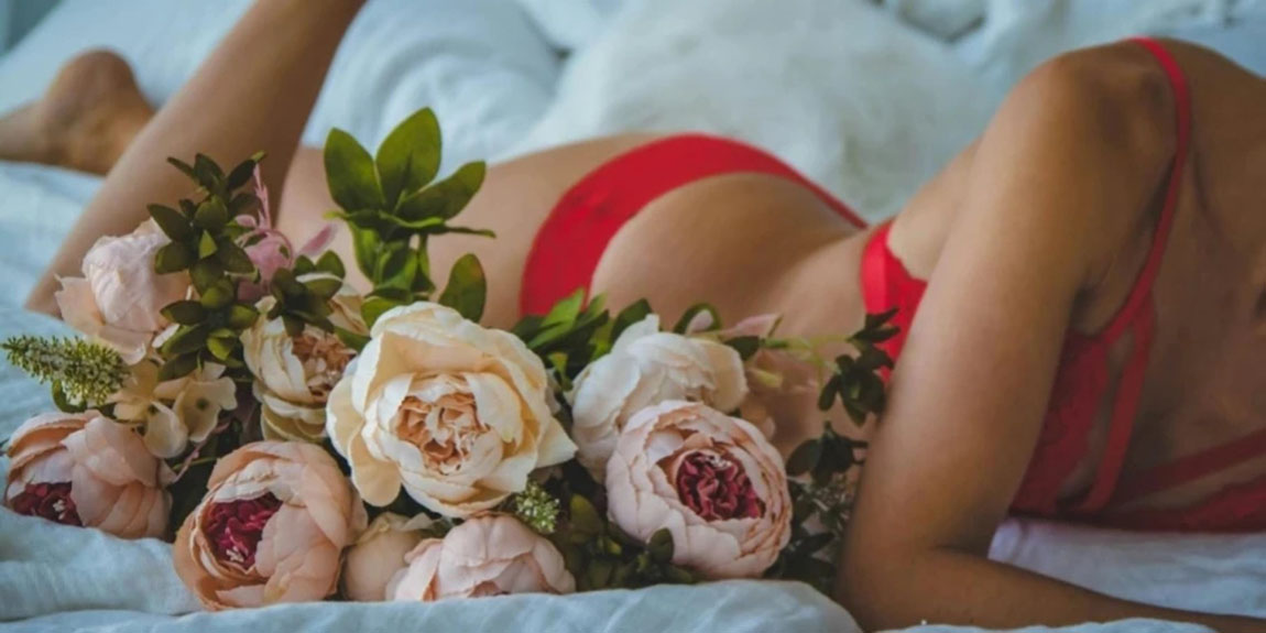 Woman-in-Red-Two-piece-Bikini-Lying-on-Bed-Beside-of-White-and-Pink-Roses.webp.jpg