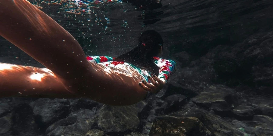 Woman-Swimming-Underwater-Above-Rocks.webp.jpg