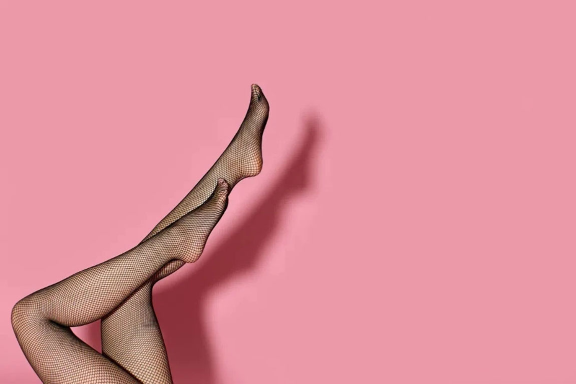 slim-female-legs-in-black-fish-net-tights-on-pink-background.webp.jpg
