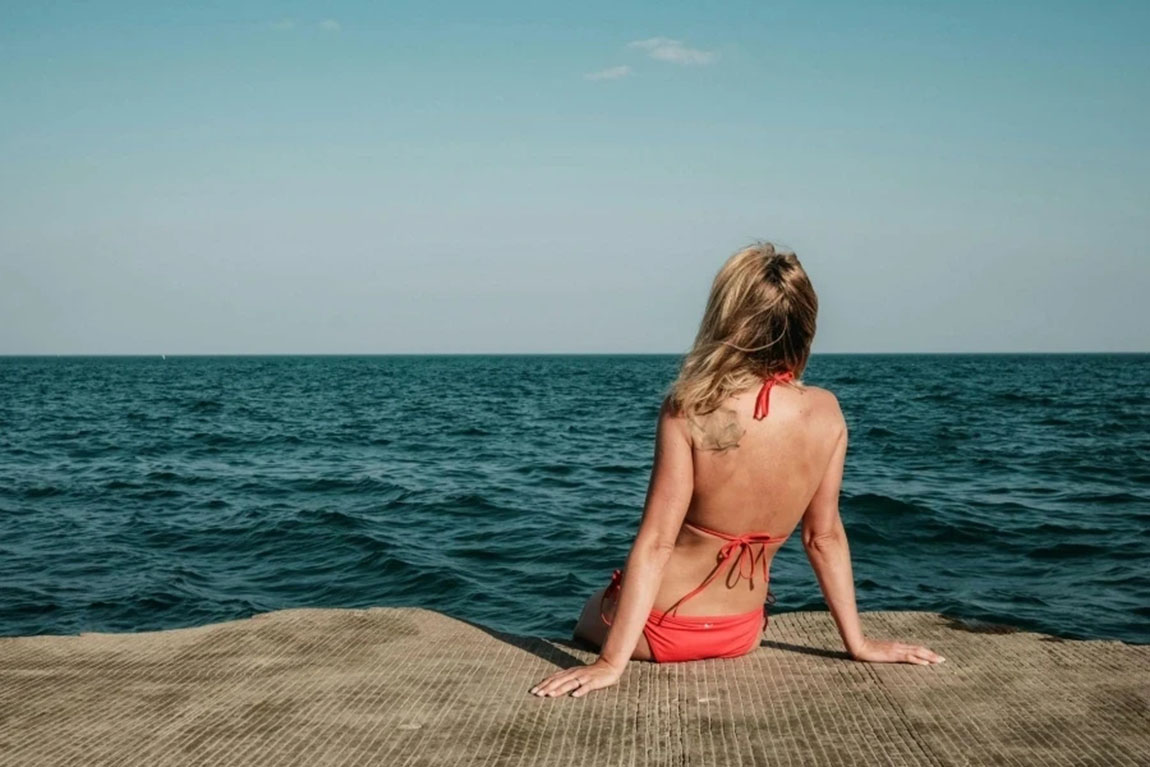 Woman-Relaxing-by-the-Ocean-on-a-Sunny-Day.webp.jpg