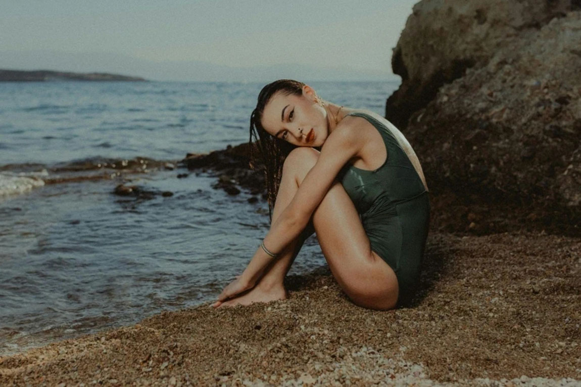 A-Woman-in-a-Swimsuit-Sitting-on-the-Beach.webp.jpg