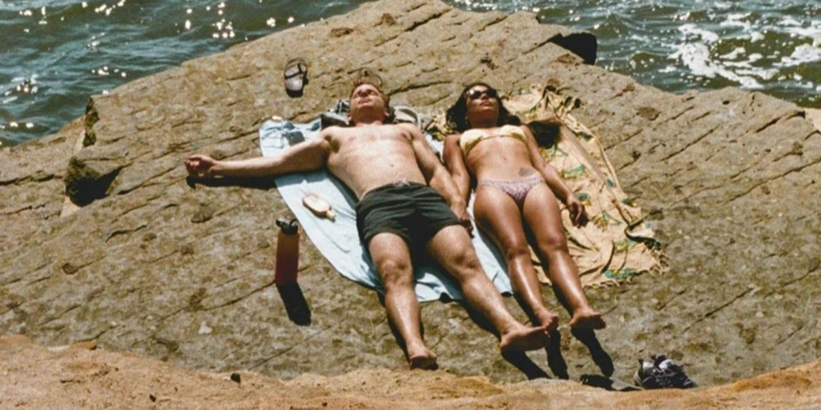 Photo-of-Couple-Lying-Down-on-Cliff-Near-Sea.webp.jpg