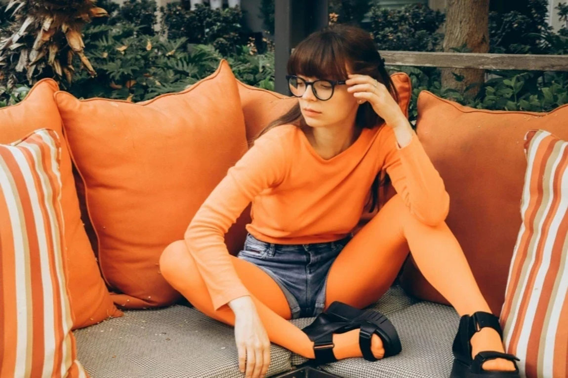 Woman-in-Orange-Clothes-Sitting-on-Patio-Sofa.webp.jpg