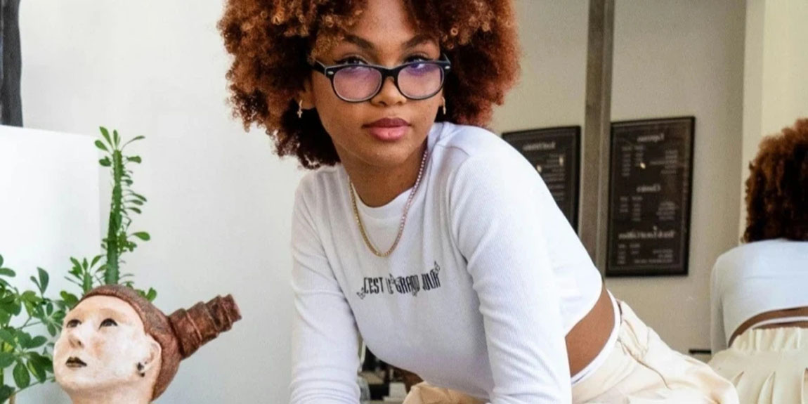 Woman-with-Red-Curly-Hair-in-Glasses-Sitting-with-Her-Back-to-Mirror.webp.jpg