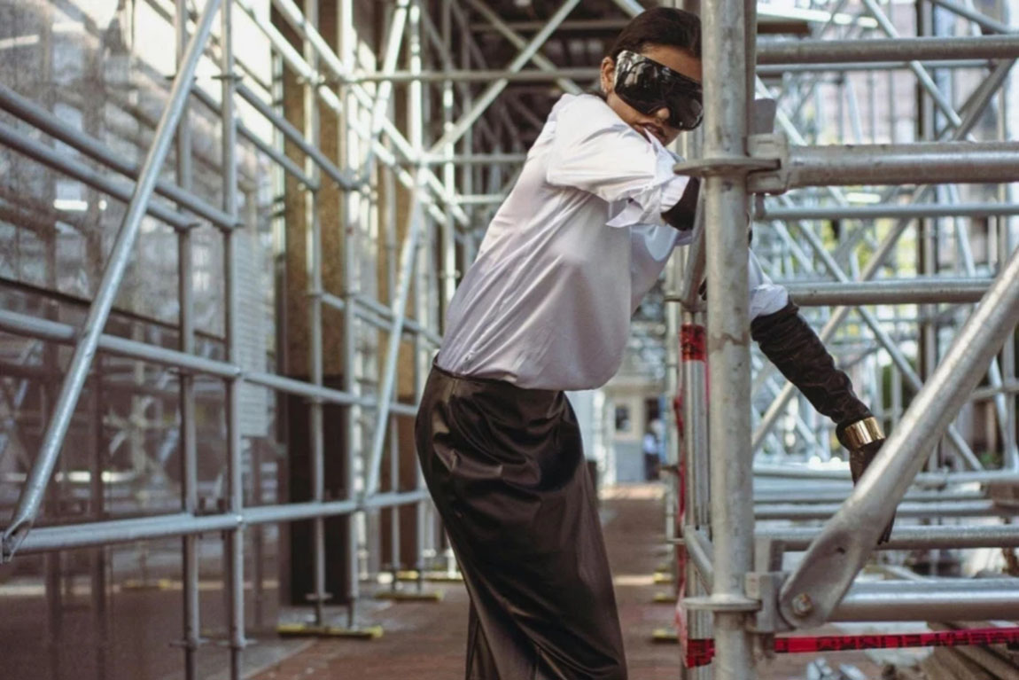 Woman-in-Goggles-and-Skirt-Standing-by-Scaffolding.webp.jpg