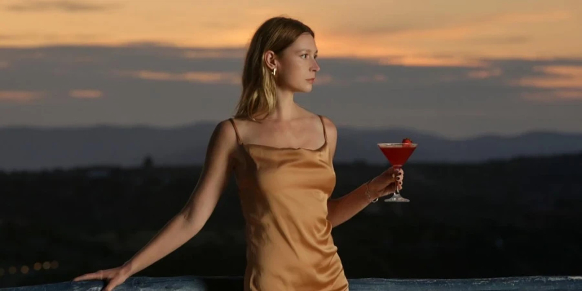 Fashionable-young-woman-holding-a-cocktail-on-beautiful-sunset-background.webp.jpg