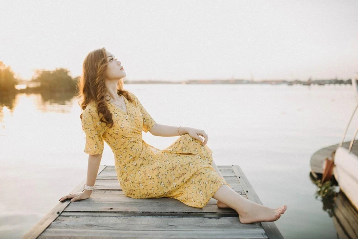 Woman-in-yellow-floral-midi-dress-sitting-on-a-deck.webp.jpg
