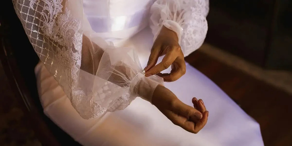 Close-up-of-a-bride-adjusting-the-lace-sleeve-of-her-elegant-wedding-dress-showcasing-delicate-details-by-Bruno-Mattos.webp.jpg