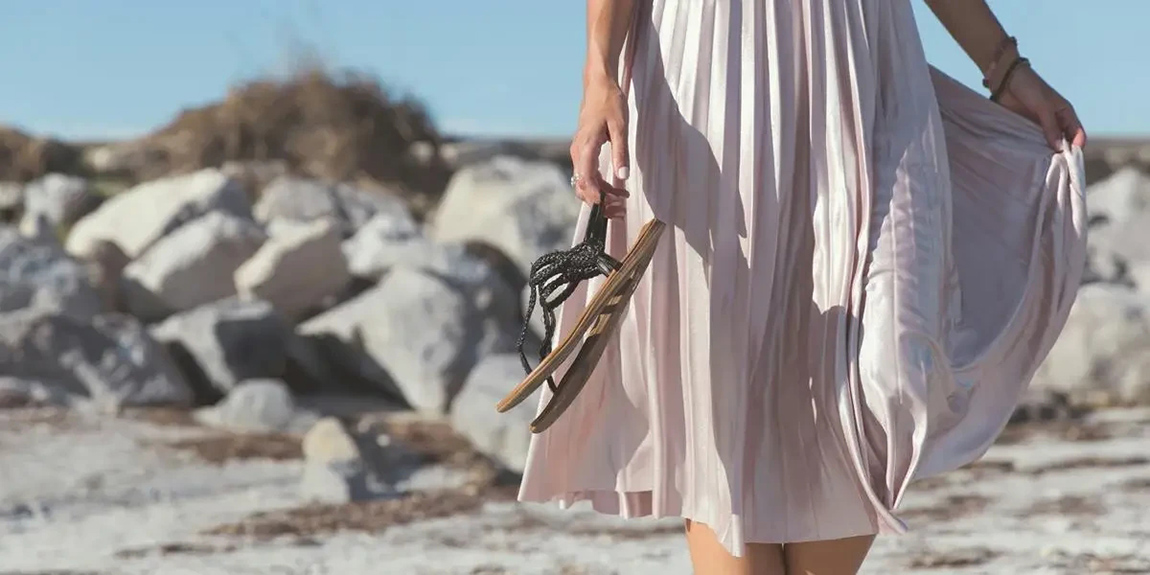 woman-wearing-white-skirt-holding-black-leather-flat-sandals-standing-by-Amelia-Bartlett (1).webp.jpg