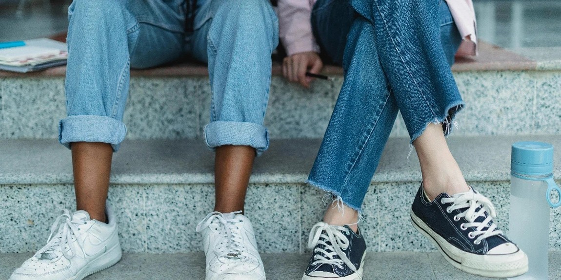 Two-friends-in-jeans-and-sneakers-sitting-on-an-outdoor-staircase-symbolizing-casual-student-life-and-friendship-by-Zen-Chung.webp.jpg