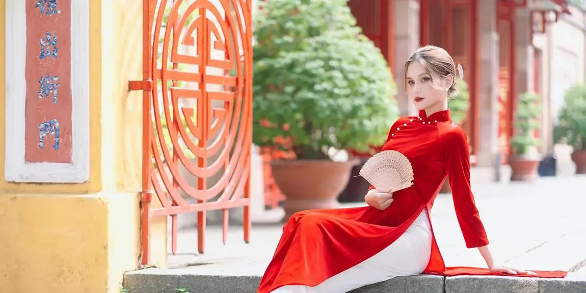 Young-woman-in-a-red-qipao-holding-a-fan-poses-gracefully-on-steps-by-Tuan-Kiet-Jr.webp.jpg