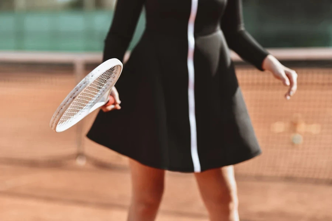 Woman-holding-white-tennis-racquet-wearing-black-and-white-dress.webp.jpg