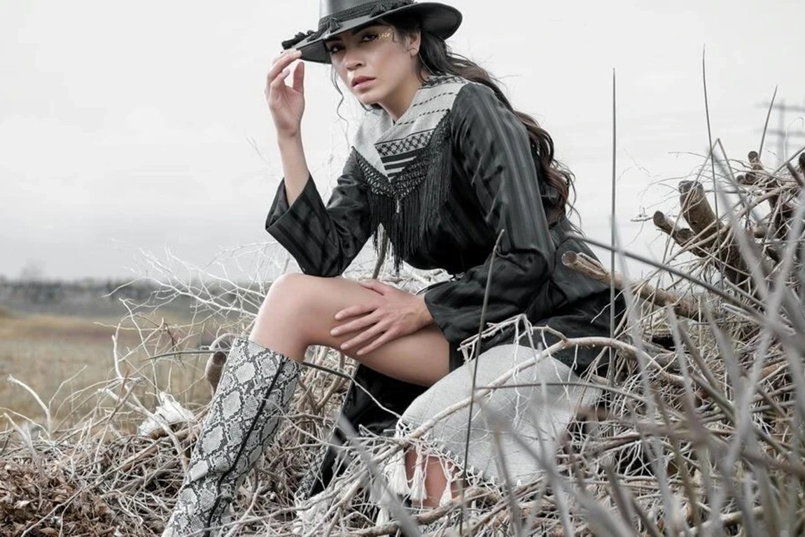 Woman-in-a-cowgirl-outfit-sitting-on-a-hay-stack.webp.jpg