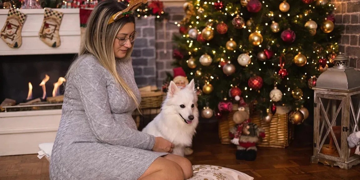 Young-beautiful-pregnant-woman-sitting-on-a-floor-and-playing-with-her-dog-in-a-cozy-Christmas-atmosphere.webp.jpg