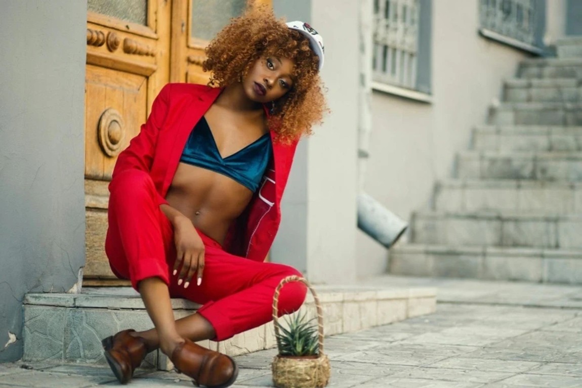 Woman-Wearing-Red-Coat-and-Pants-Sitting-Outside-Gray-Building.webp.jpg