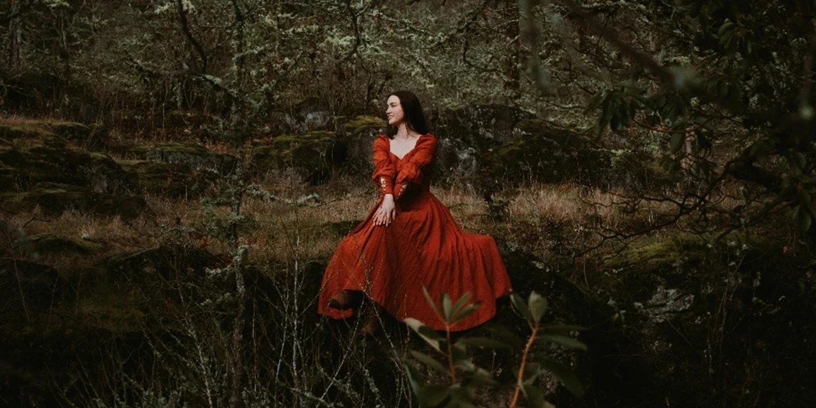Woman-in-a-Red-Medieval-Dress-Sitting-on-a-Rock-in-the-Forest-by-Lance-Reis.webp.jpg